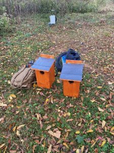 Two owl boxes ready to be hung in a tree.